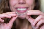 Adult over 40 smiling while wearing Invisalign clear aligners for teeth straightening